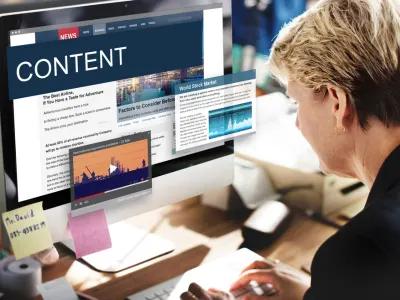 Content creator reviewing news website layout and articles on desktop screen, showcasing digital content strategy for writing agency clients.