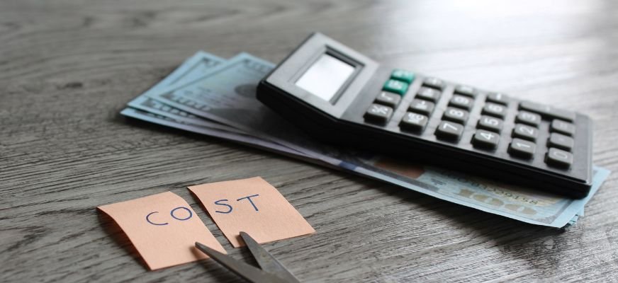 Calculator with paper currency shows financial cost analysis tools used by customer retention advisors.