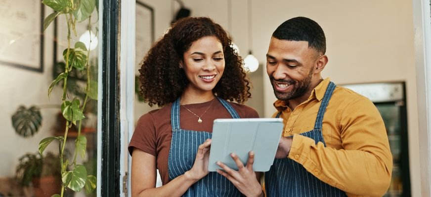 Two business owners using a tablet, representing the benefits of local SEO services.
